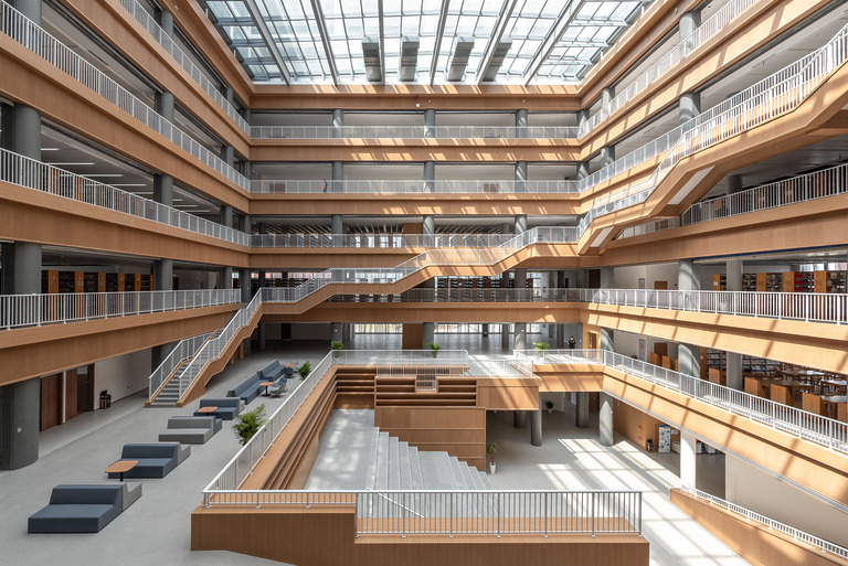 Lichtdurchflutetes Atrium einer Universitätsbibliothek mit Treppen und Regalen