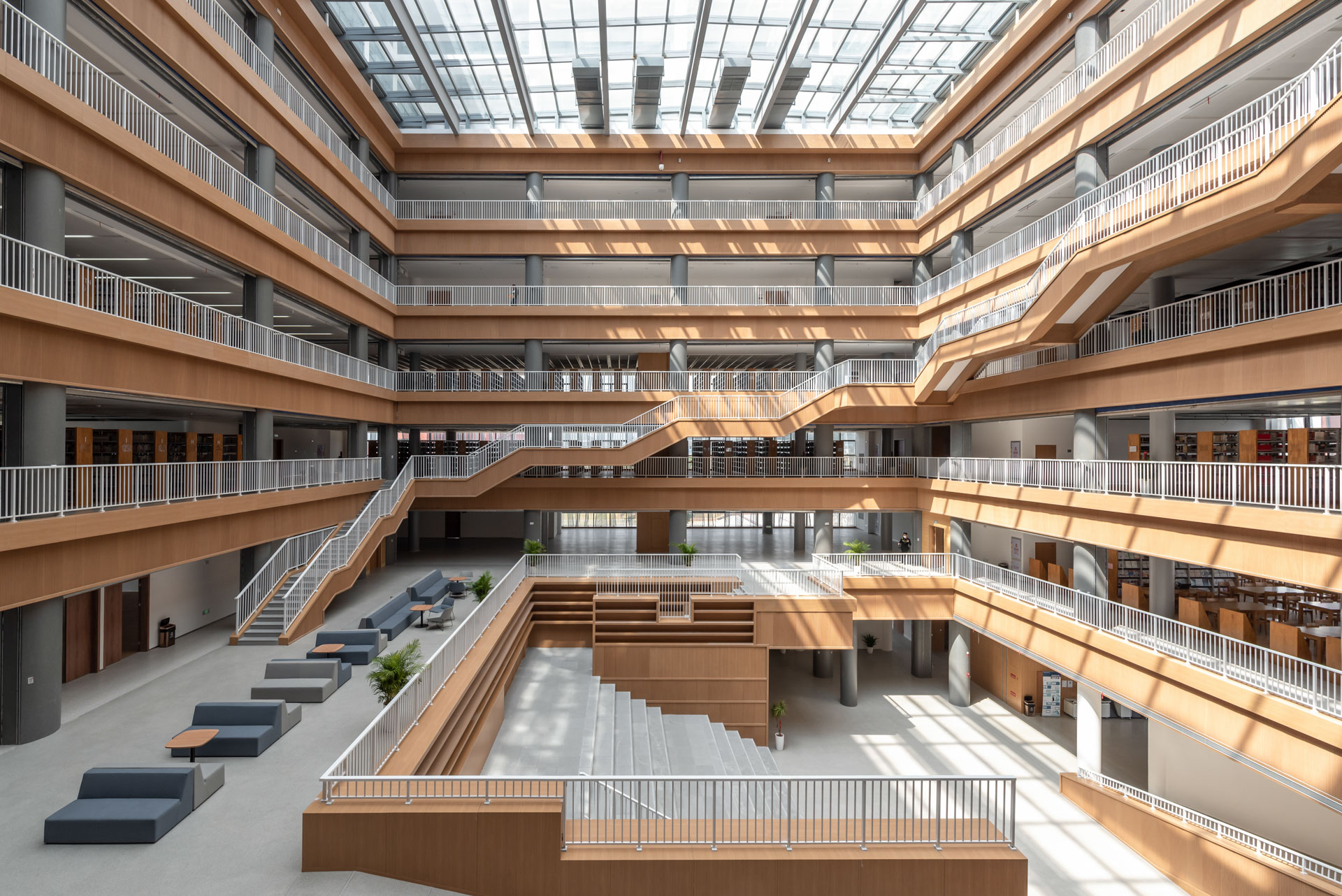 Lichtdurchflutetes Atrium einer Universitätsbibliothek mit Treppen und Regalen