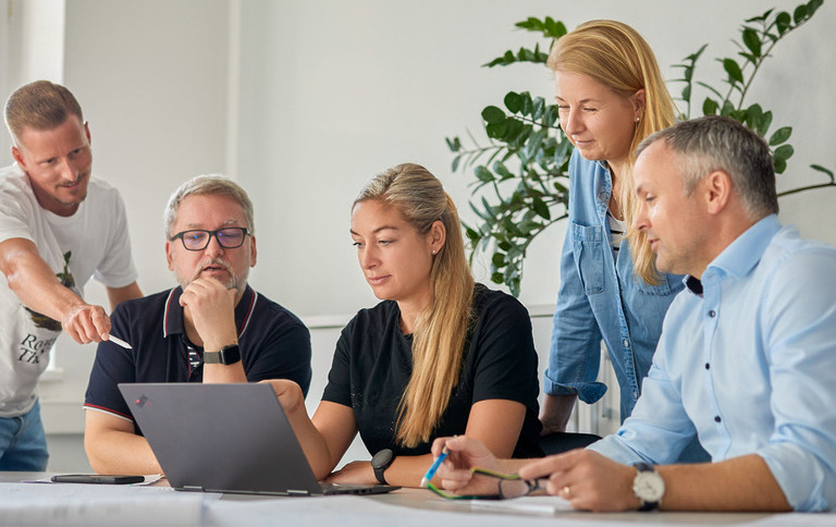 Genius-Mitarbeitende besprechen ein Projekt am Laptop